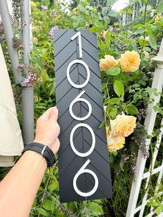 a person holding up a sign that reads 1, 0000 in front of some flowers