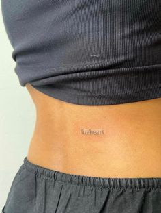 a woman's stomach with the word flesheat tattooed on her lower back