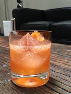 an orange drink sitting on top of a wooden table