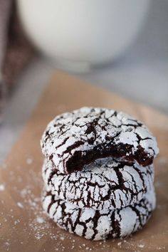 two chocolate crinkle cookies sitting on top of a piece of paper