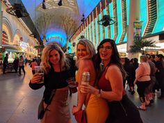 three beautiful women standing next to each other holding wine glasses in their hands and smiling at the camera