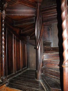 an old wooden staircase leading up to the second floor in a house with dark wood paneling