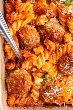 a casserole dish with meatballs and pasta in it, topped with parmesan cheese