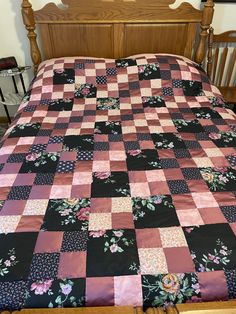 the bed is made up with pink and black quilts on it's sides