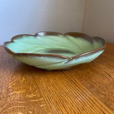 a green bowl sitting on top of a wooden table