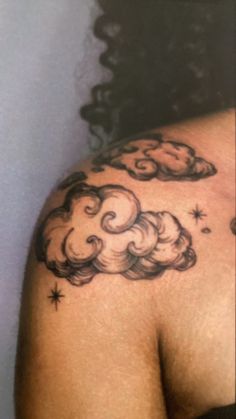 the back of a woman's shoulder with clouds and stars on it