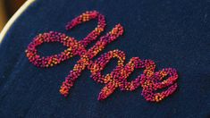 the word hope is made out of beads on a piece of blue fabric with pink and orange letters