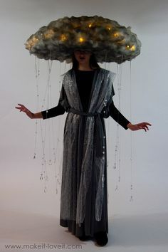 a woman in a black dress with a cloud on her head and lights hanging from it's sides