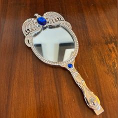 a mirror sitting on top of a wooden table next to a mirror with blue stones