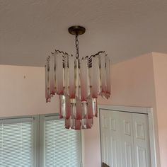 a chandelier hanging from the ceiling in a room with pink walls and windows