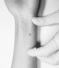 a small heart tattoo on the left side of the wrist is shown in black and white