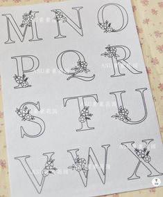 the letters and numbers are drawn with black ink on white paper, which is decorated with flowers