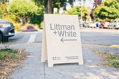 a sign on the sidewalk that says, littleman + white with an arrow pointing to it