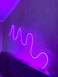 a purple wall with a neon sign on it