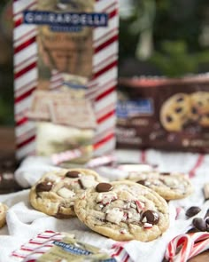 chocolate chip cookies with white and red sprinkles are on a table next to a box of milk