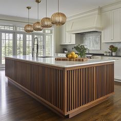 a large kitchen island with wooden cabinets and hanging lights