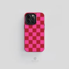 a pink and red checkered phone case sitting on top of a white surface,