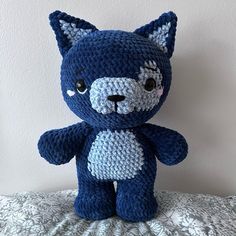 a blue crocheted teddy bear sitting on top of a bed