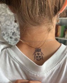 a ladybug tattoo on the back of a woman's neck is shown