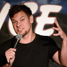 a man standing in front of a microphone with his hand up to the camera and holding it out