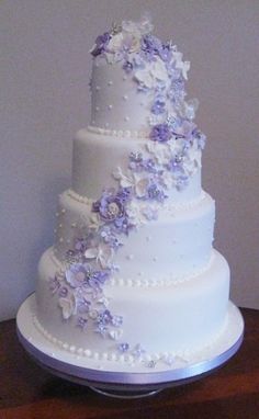 a three tiered white wedding cake with purple flowers