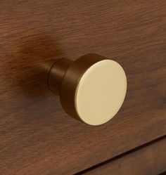 a close up of a wooden drawer with a white knob on the top and brown handles