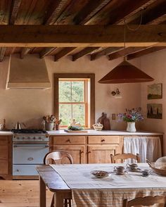 a kitchen with an oven, table and chairs next to a window in the wall