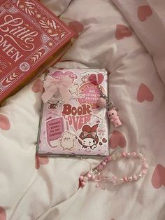 a pink book laying on top of a bed next to a heart - shaped pillow