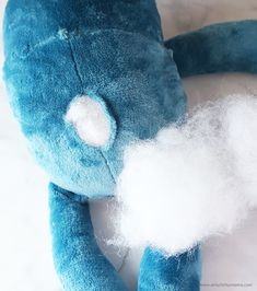 a blue stuffed animal with white patches on it's eyes and nose sitting next to cotton floss