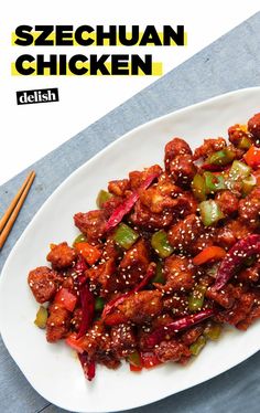 a white plate topped with meat covered in sesame seeds and veggies next to chopsticks