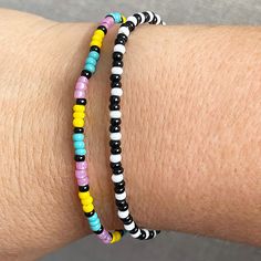 two bracelets on someone's arm with multicolored beads