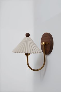 a wall mounted light with a green shade on it's side and a wooden arm