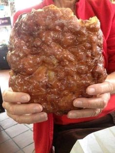 a woman holding up a large piece of food