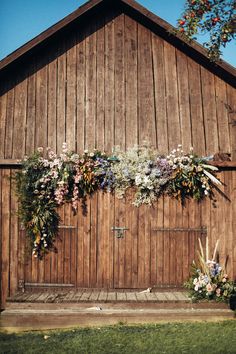 a wooden building with flowers on the side and grass growing up to it's door