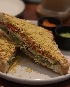 a sandwich cut in half sitting on top of a plate next to dipping sauces