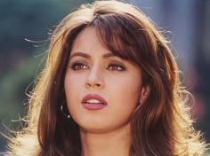 a close up of a woman with long hair and brown eyeshadow, looking at the camera