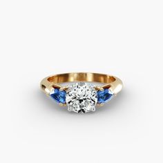 a diamond and blue sapphire engagement ring in yellow gold with an oval center stone on the side