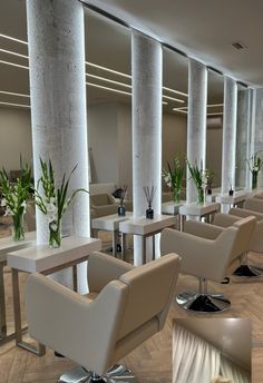 an empty restaurant with white chairs and tall columns on the wall, along with potted plants in vases