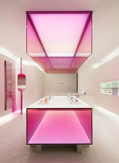 a pink and white bathroom with lights on the ceiling, counter top and sink area