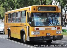 a yellow bus is driving down the street with other cars behind it and trees in the background