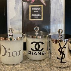 three silver canisters sitting on top of a table next to a chanel sign