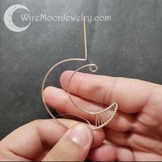 a person is holding a wire wrapped around a spiral brooch in their left hand