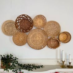 wicker baskets are arranged on the wall above a table with candles and vases