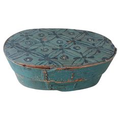 an old wooden box with blue paint on it's lid and floral designs in the middle