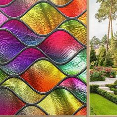 a colorful stained glass window in front of a house with trees and bushes around it