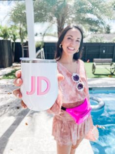 a woman is holding up a pink and white cup with the letter jd on it