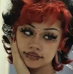 a woman with red hair and piercings on her face is looking at the camera