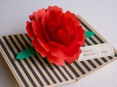 a red paper flower sitting on top of a piece of brown paper next to a tag