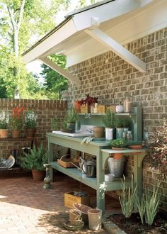 an outdoor kitchen with potted plants and pots on the outside wall, next to a garden bench