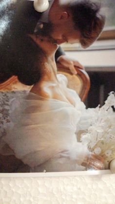 a bride and groom kissing in front of a cake with white frosting on it